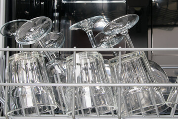 transparent glasses for wine and water in the basket of the dishwasher, close-up