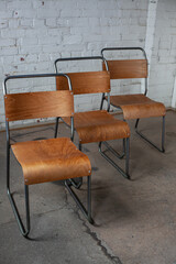 Wooden and metal chairs in room against white bricks wall
