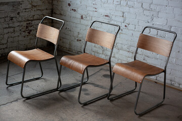 Wooden and metal chairs in room against white bricks wall