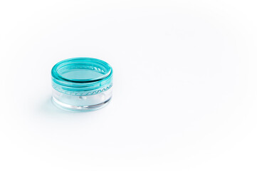 Empty small plastic or glass jar for beauty cream on white background. Close transparent container with a blue lid. Acrylic container for skin care cosmetics.