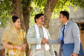 Rural Indian couple with farmer and bank executive shaking hands in village