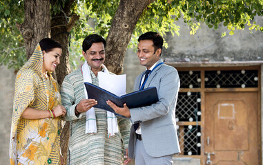 Rural Indian couple with farmer and bank executive shaking hands in village