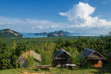 Fototapeta na wymiar wooden homestay cabin or hut view from Samed Nangchee viewpoint, Phang Nga, Thailand. Beautiful seascape of jame bond island at Antaman sea with blue sky.