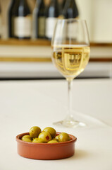 Glass of white wine with green olives