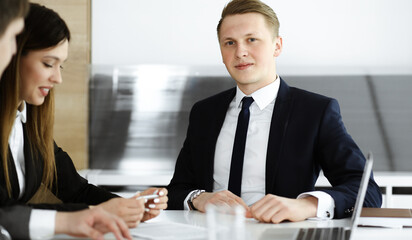 Businessman at meeting in modern office. Unknown entrepreneur sitting with diverse colleagues at the background