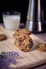 Chocolate cookies with a glass of milk and a jug of coffee on a wooden table