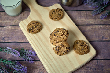 Chocolate cookies with a glass of milk and a jug of coffee on a wooden table