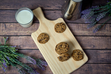 Chocolate cookies with a glass of milk and a jug of coffee on a wooden table