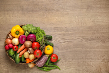 Different fresh vegetables on wooden table, flat lay. Space for text
