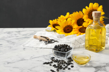 Sunflower oil and seeds on white marble table, space for text