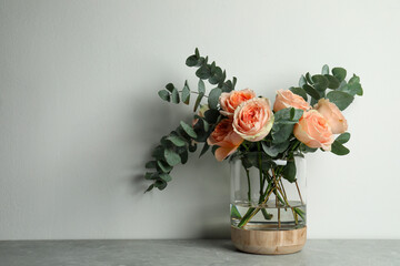 Bouquet of beautiful flowers in glass vase on grey table against white background. Space for text © New Africa
