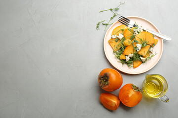 Fototapeta na wymiar Delicious persimmon salad with blue cheese and orange served on light grey table, flat lay. Space for text
