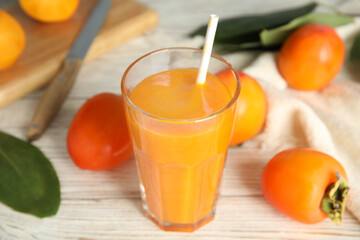 Tasty persimmon smoothie and fresh fruits on white wooden table, closeup