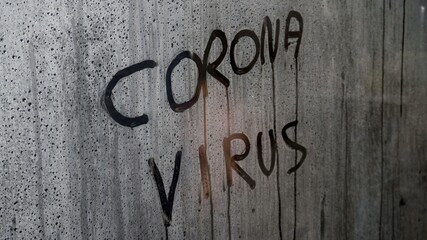 written Covid-19 Coronavirus on a fogged glass - hand erases the writing - concept of the end of the pandemic thanks to the arrival of the vaccine