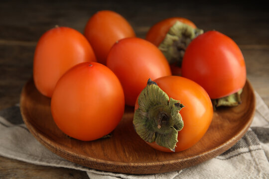 Tasty ripe persimmons on wooden table, closeup