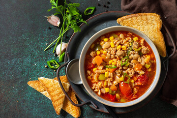 Traditional mexican food. Chili con carne, minced meat with vegetables on dark stone table. Top view flat lay.