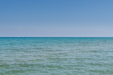 Fototapeta na wymiar Lots of tourists swimming in the sea in summer near Larnaca Finikoudes beach of Cyprus