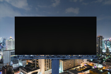 Blank black road billboard with Bangkok cityscape background at night time. Street advertising poster, mock up, 3D rendering. Front view. The concept of marketing communication to sell idea. © VideoFlow