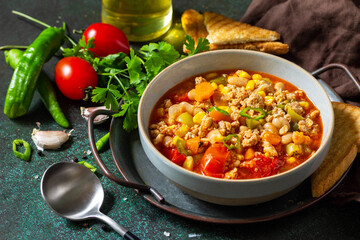 Traditional mexican food. Chili con carne, minced meat with vegetables on dark stone table.