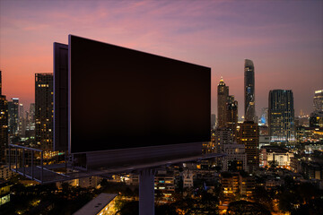 Blank black road billboard with Bangkok cityscape background at night time. Street advertising...