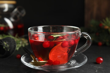 Tasty hot cranberry tea with rosemary and lemon on black table
