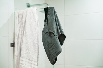 Gray men's underwear and towel white hangs on the glass of the shower. Bathroom. Washing. Male. Sex. Intimacy. Intimate. Clothes. Mess. Rest room. Water. Wash. Ready