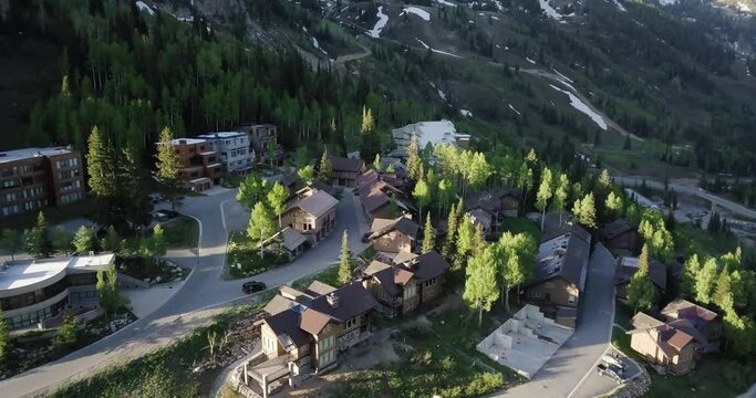 A drone flight over a small village like ski resort in the mountains of Utah as the sun rises in spring.