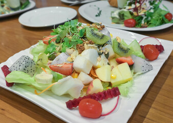 Fresh mix vegetables and fruits salad on wooden table.