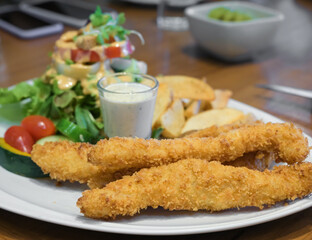Fish and chips served with tarter sauce and green salad.
