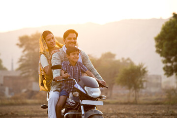 Happy rural Indian family riding on motorcycle