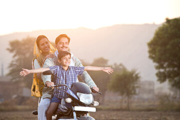 Happy rural Indian family riding on motorcycle