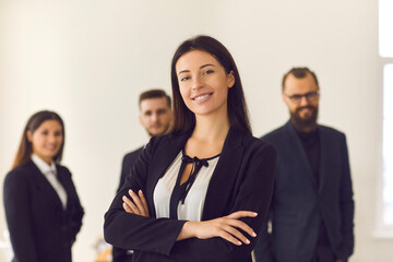 Portrait of a smiling pretty young business woman on the background of employees.