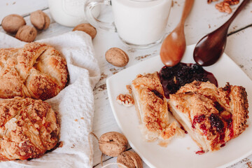 On the table, fresh homemade cakes are cut into pieces. served with berry jam. Wooden spoons for jam. pour the milk into the cup.