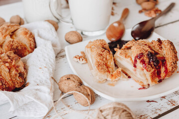 On the table, fresh homemade cakes are cut into pieces. served with berry jam. Wooden spoons for jam. pour the milk into the cup.
