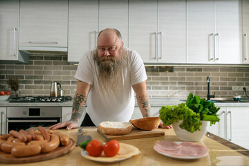 Emotional fat funny and tattooed man with food at the kitchen at home