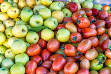 A market stall with yellow apples and tomatoes for salad.