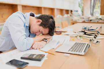 Obraz premium handsome businessman sleepy before working with laptop at desk in office. Working late night and start working early in the morning.