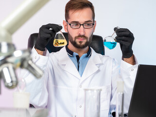 The chemist compares the chemical liquid in test tubes. A scientist is sitting at a table in a chemical laboratory. Chemical experiments. Development of new types of fuel.