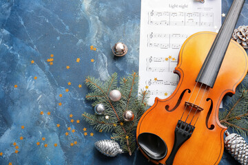 Violin with Christmas decor and music notes on color background