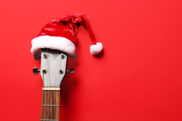 Guitar with Santa Claus hat on color background