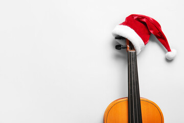 Violin with Santa Claus hat on light background