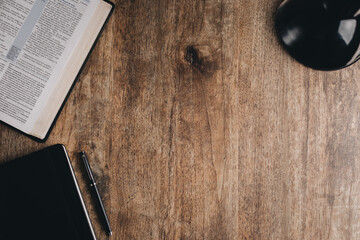 An open bible and notebook for bible study on a wooden desk. Top view flat lay.