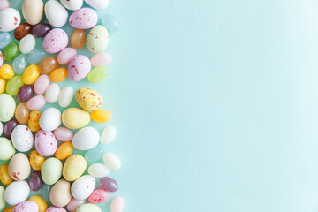Happy Easter concept. Preparation for holiday. Easter candy chocolate eggs and jellybean sweets isolated on trendy pastel blue background. Simple minimalism flat lay top view copy space.