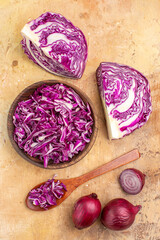 top view chopped red cabbage in a wooden bowl and several red onions are ready for beet salad on a wooden background