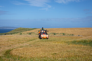 crop sprayer treats field of barley on north coast northern ireland