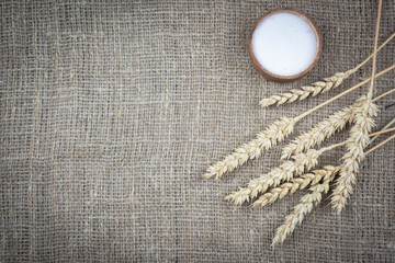 Background: wheat ears and a jar of salt on a coarse cloth