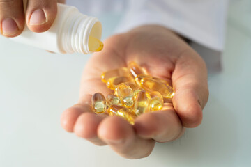 close up of man pouring fish oil capsules to hand