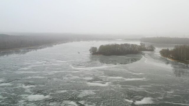 top view of an island in the middle of a frozen lake and fishermen catching fish
