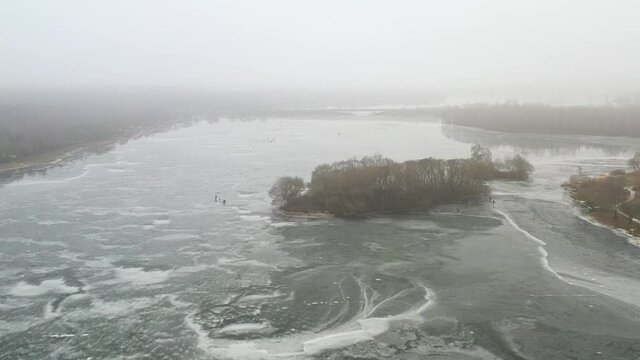 top view of an island in the middle of a frozen lake and fishermen catching fish