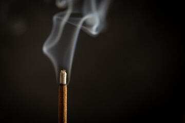Asian incense stick burning with smoke, close up, macro